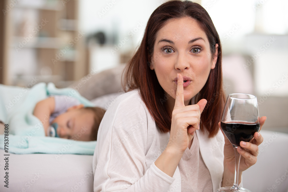 mother drink wine while baby sleeping in background mother drink wine while baby sleeping in background