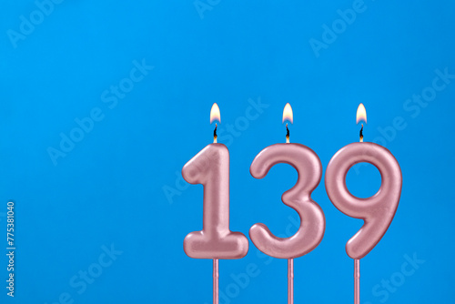 Number 139 - Burning anniversary candle on blue foamy background