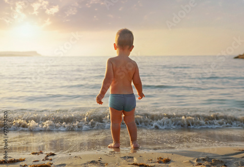 A boy stands on the beach and looks at the sea.Vacation with children.Happy lifestyle childhood concept.View from back