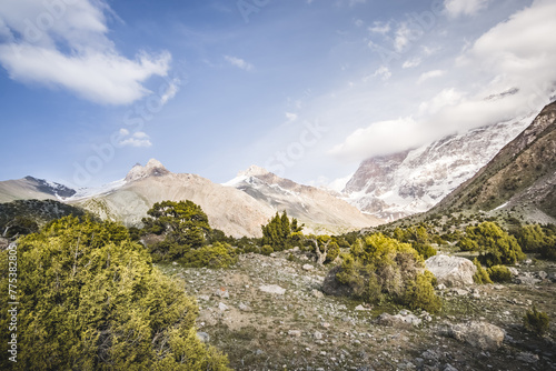 Mountain panoramic landscape of the Fan Mountains with rocks, glaciers and vegetation in sunny weather with blue sky, mountain panorama in Tajikistan in the early evening photo