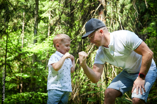 Father and Son Enjoying Playful Fist Bump in Lush Forest © keleny