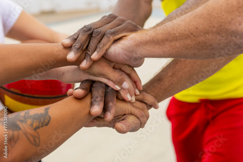 Basketball anonymous teammates place their hands together in a symbol of unity and shared commitment before starting their street basketball session photo