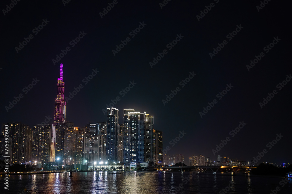 The Saigon river with the skyline of Ho Chi Minh City (Saigon), Vietnam, and the purple illuminated tower Landmark 81 in the background at night The Saigon river with the skyline of Ho Chi Minh City (Saigon), Vietnam, and the purple illuminated tower Landmark 81 in the background at night