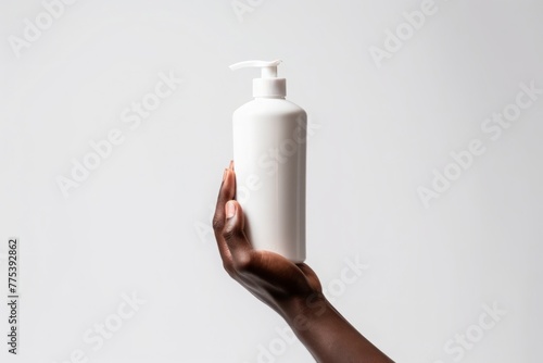 A dark-skinned hand elegantly holds a white tube of cosmetic product with a minimalist background