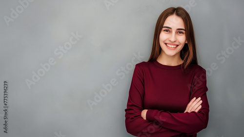 Mulher sorrindo de braços cruzados vestindo vinho no fundo cinza