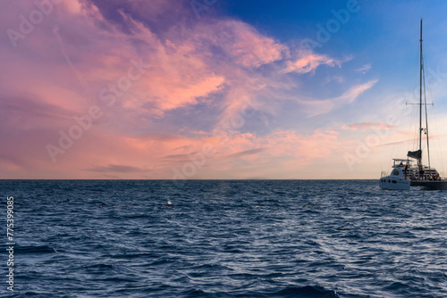 A boat sailing on the rippling blue waters of the Pacific Ocean off the coast of Oahu at sunset at Ko Olina in Kapolei Hawaii USA photo