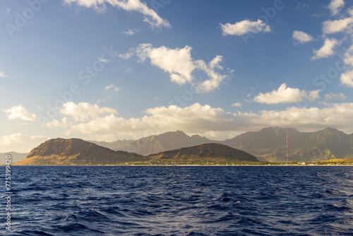 a beautiful spring landscape of the coast of Oahu with majestic mountain ranges, lush green trees and plants, rippling blue ocean water and blue sky with clouds at sunset in Kapolei Hawaii USA photo