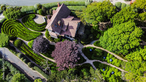 Drone view on Part of Etretat gardens with amazing curves of topiary bushes and red leaves trees and house photo