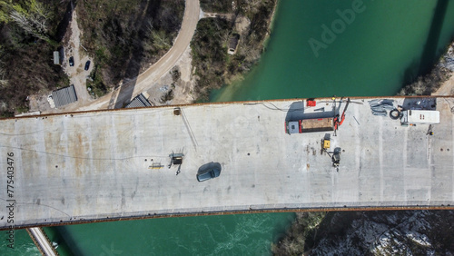 Construction of a high bridge over the river, aerial drone view. Workers and machines on construction site. Highway bridge.