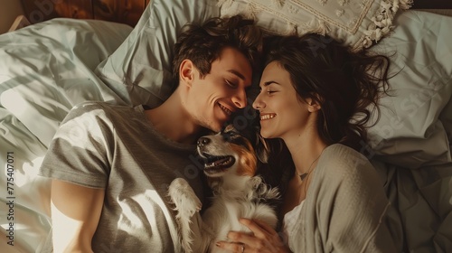 Young couple in love lying on the sofa in the bedroom with their beloved dog, having fun and enjoying each other on their weekend. 