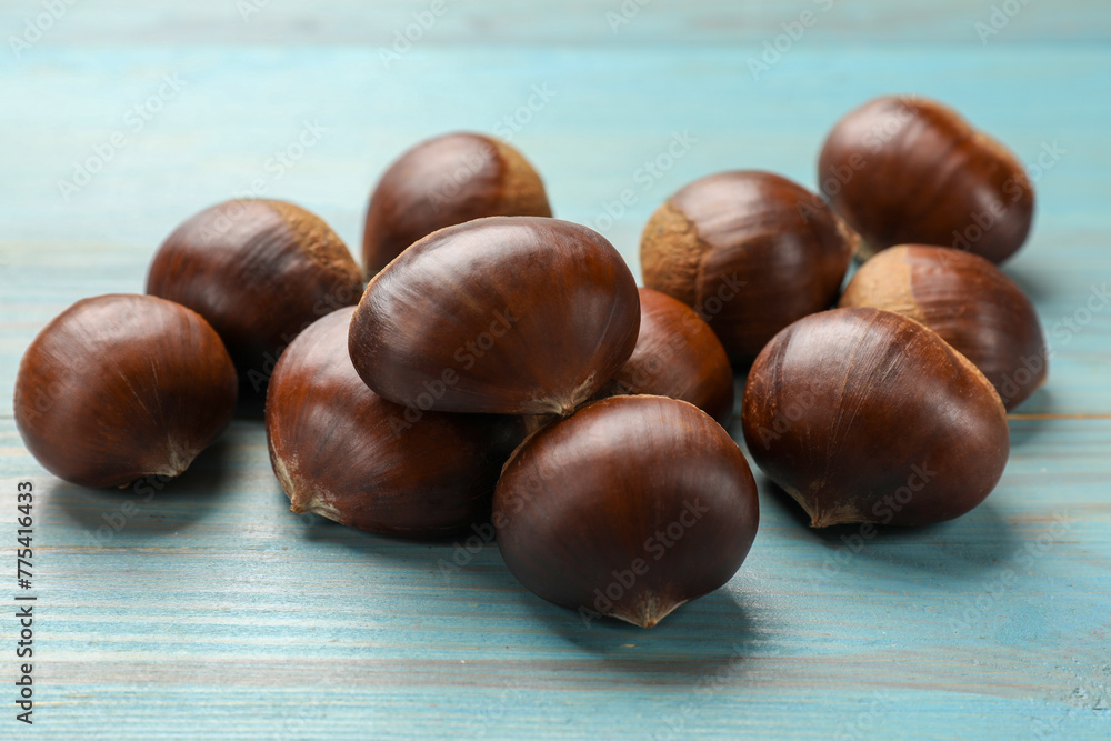Roasted edible sweet chestnuts on light blue wooden table, closeup Roasted edible sweet chestnuts on light blue wooden table, closeup