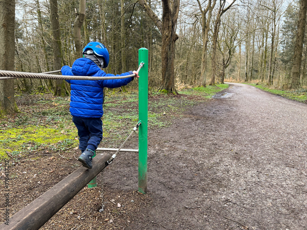 Fototapeta premium Little toddler climbing and playing in the forest, Flensburg northern city in Germany