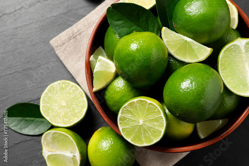 Fresh ripe limes in bowl on black table, top view