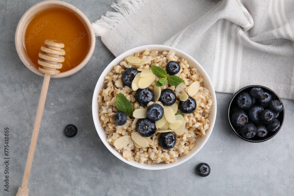 Tasty oatmeal with blueberries, mint and almond petals in bowl on grey table, flat lay Tasty oatmeal with blueberries, mint and almond petals in bowl on grey table, flat lay