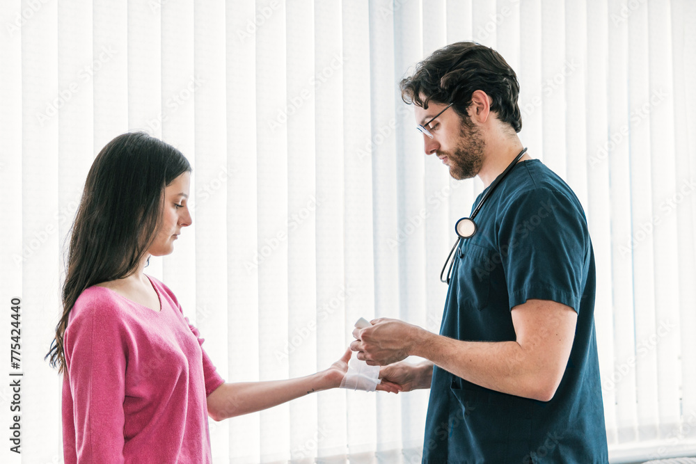 A caring doctor is seen carefully wrapping a bandage around a patient's wrist, demonstrating thorough wound care A caring doctor is seen carefully wrapping a bandage around a patient's wrist, demonstrating thorough wound care