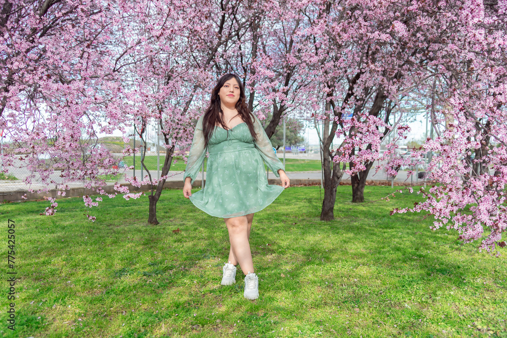 Woman in green dress enjoying cherry blossom season Woman in green dress enjoying cherry blossom season