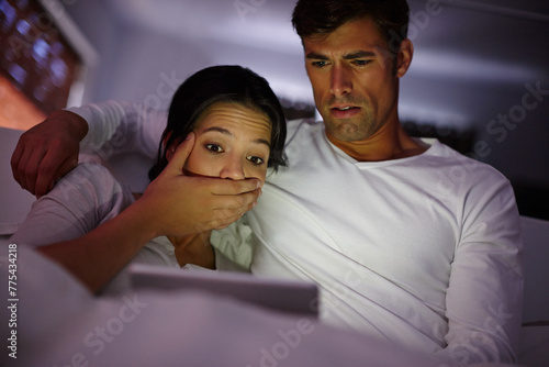 Couple, tablet and scary movie at night, watching and streaming film online on app or website in home. People, entertainment and relax in embrace, bonding and crazy horror series on internet in dark