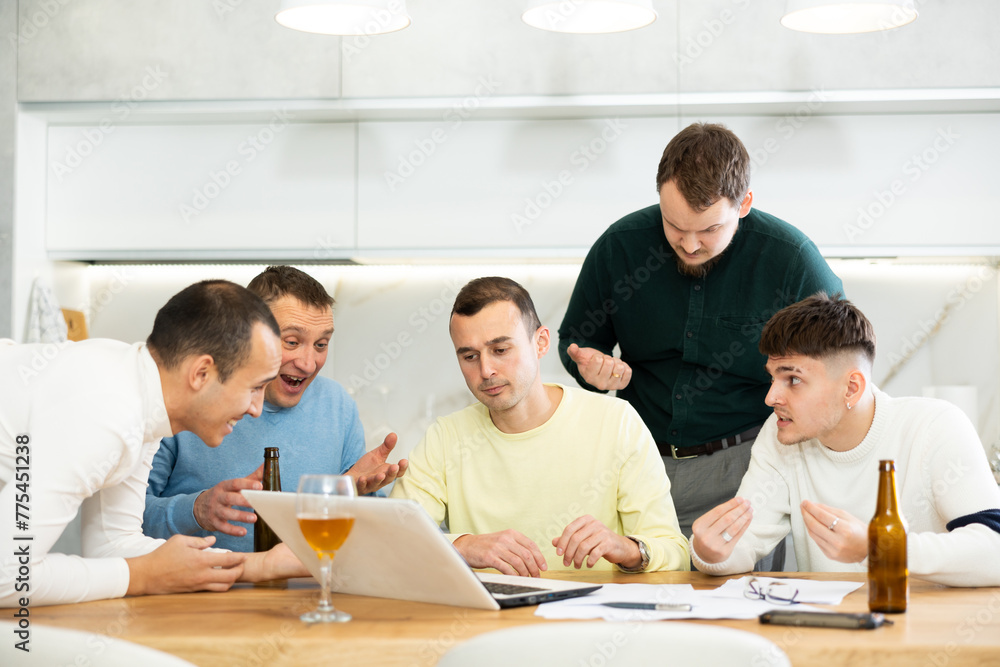 Men drink beer and try to help friend solve problems using laptop and the Internet