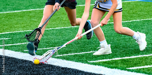 An offensive player with the ball is being chased by the defense. Girls varsity lacrosse game in early Spring in Upstate NY. photo