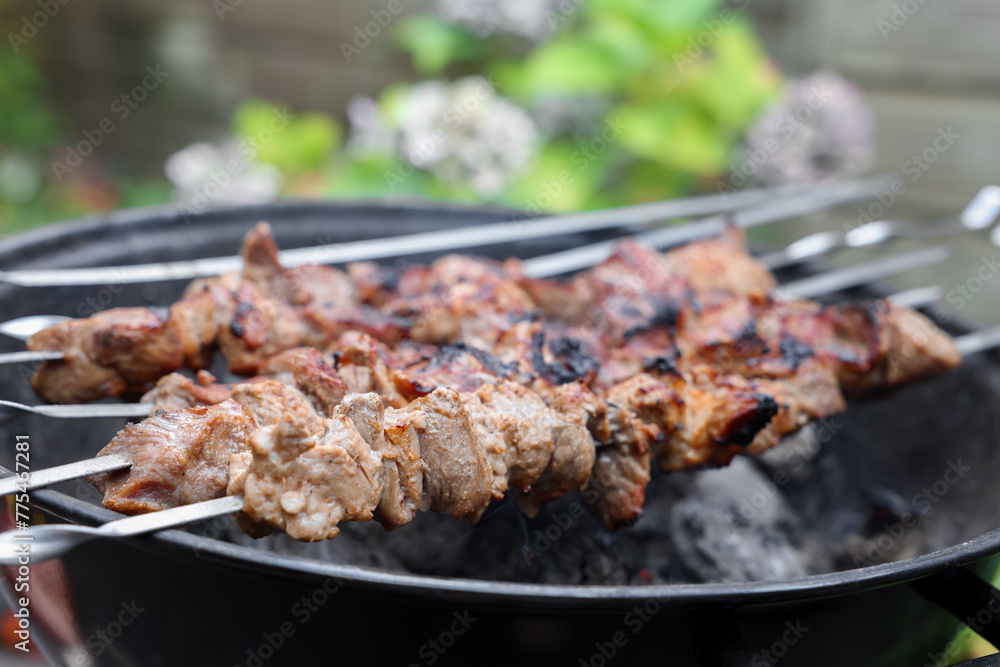Cooking delicious kebab on metal brazier outdoors, closeup