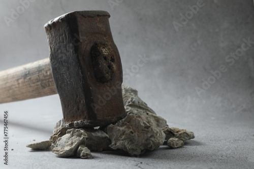 One sledgehammer and pieces of broken stones on grey background, closeup. Space for text photo