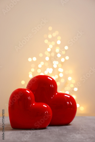 Red ceramic hearts on grey table against blurred lights © New Africa