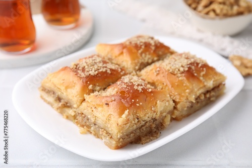Eastern sweets. Pieces of tasty baklava and tea on white tiled table, closeup