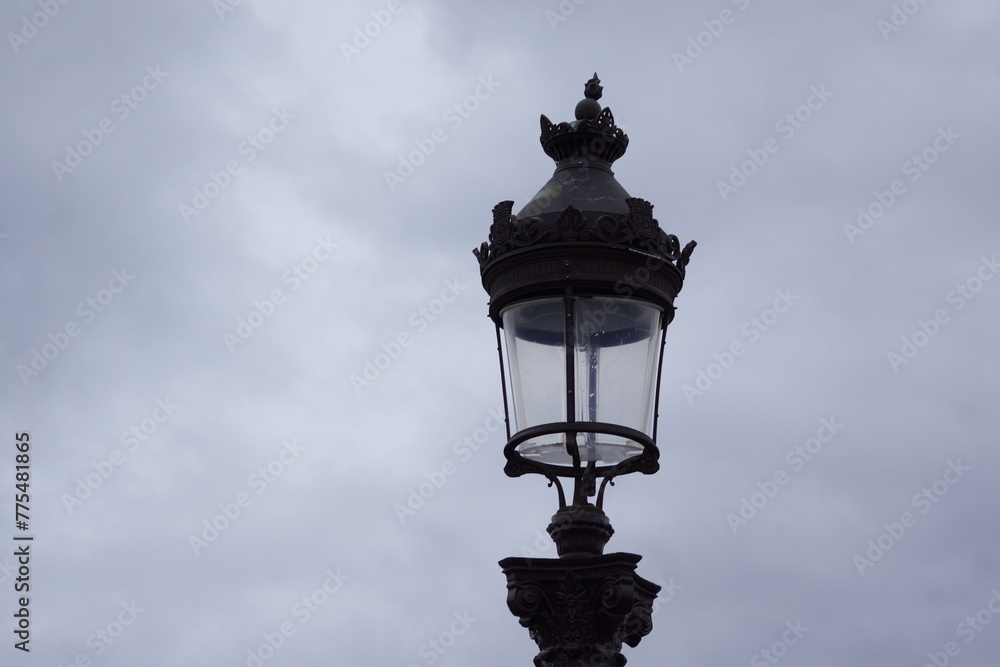 Antique black street lamp under cloudy sky