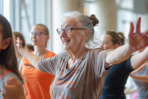 A woman in glasses and a gray shirt is smiling while dancing with other people. Scene is joyful and lively