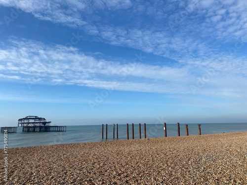 Pier in calm blue water under summer sky at Brighton in Sussex, England. Ruin of west pier on sunny bright day 