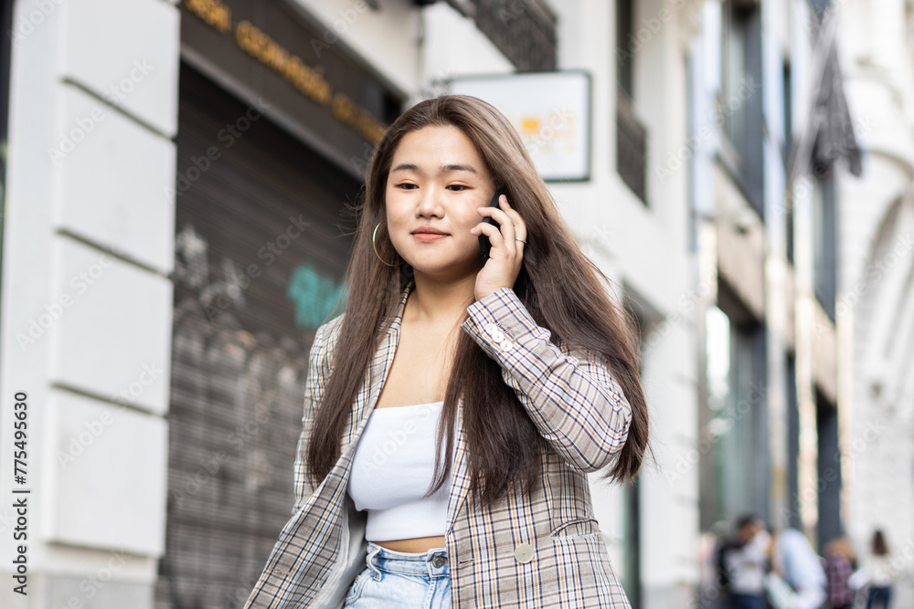 Fototapeta premium Young asian woman talking on the phone in the city