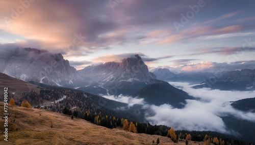 mountains in fog at beautiful sunset in autumn in dolomites italy landscape with alpine mountain valley low clouds trees on hills purple sky with clouds at dusk aerial view passo giau nature © Adrian