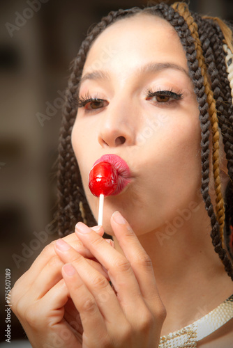 Portrait of beautiful young Latina woman kissing a candy pop.