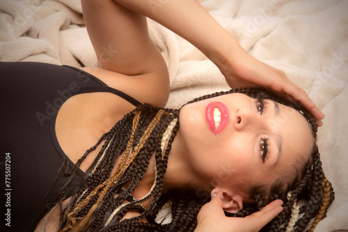 Beautiful young Latina woman reclining into a tan blanket.