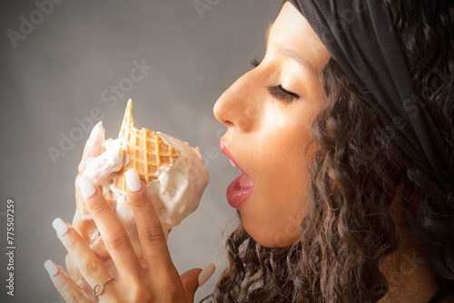 Closeup of beautiful young woman eating an ice cream cone.