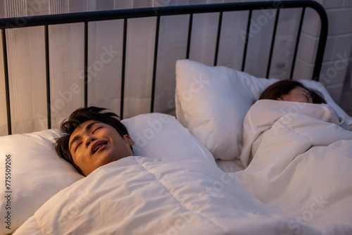 Asian woman feel frustrated from husband snoring while sleep at night.