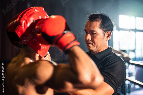 Asian fitness trainer support Caucasian sportsman doing boxing in gym.  © Kawee