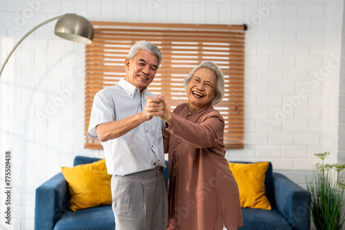 Asian active senior couple enjoy dance together in living room at home. 