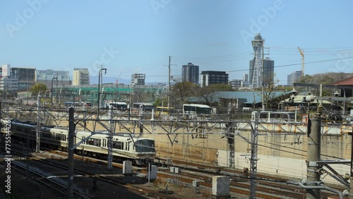Train on the railroad with Osaka cityscape in the background with Tsutenkaku Tower photo