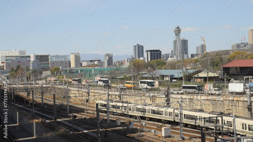 Train traveling on railway track with Osaka cityscape in the background with Tsutenkaku Tower Train traveling on railway track with Osaka cityscape in the background with Tsutenkaku Tower