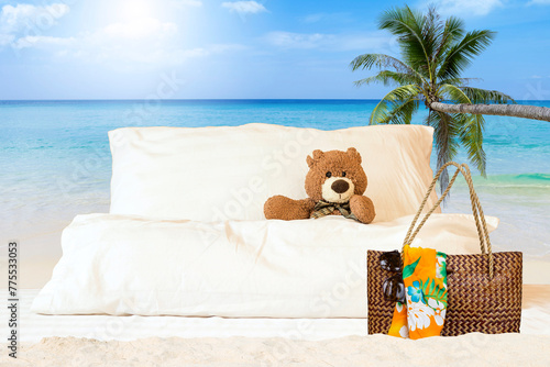 Happy Teddy bear in bed with summer bag over tropical beach background, summer holiday and vacation, tourism industry concept
