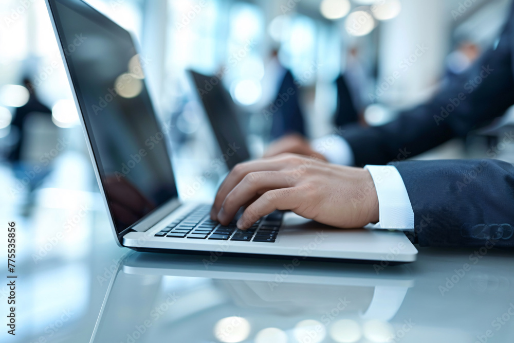 A businessman typing on a laptop computer at his office desk A businessman typing on a laptop computer at his office desk