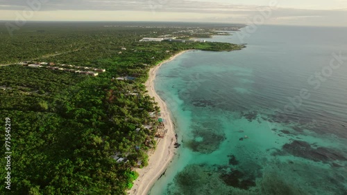 Aerial Dolly out in caribian beach.  white sand, crystal-clear waters with coral reefs surrounded by rainforest  at sunrise. Riviera maya, Quintana roo, Mexico.
 photo