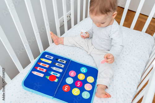 Baby happily plays with felt board in crib