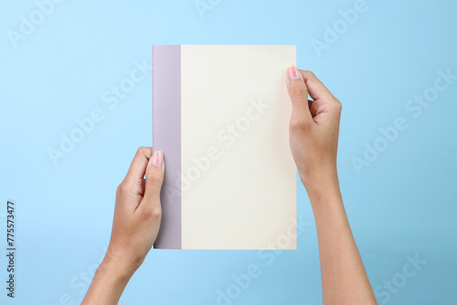Woman holding yellow book with blank cover for mockup isolated on blue background