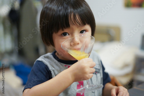 カクテルグラスでオレンジジュースを飲む子供 / Child drinking orange juice in a cocktail glass