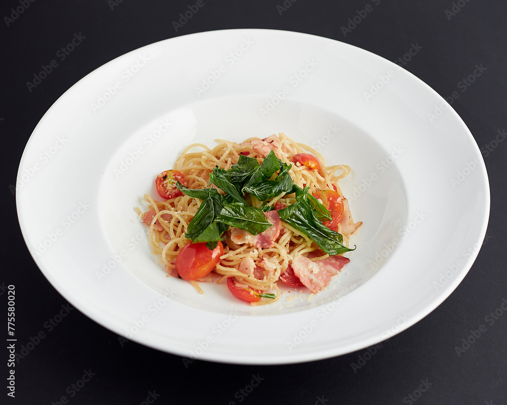 Spaghetti with ham, tomatoes and cheese served in white plate isolated on black background. italian food. Spaghetti with ham, tomatoes and cheese served in white plate isolated on black background. italian food.
