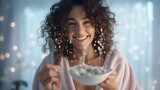 Close up portrait of happy smiling brunette in bathrobe holding cereals in spoon eating breakfast