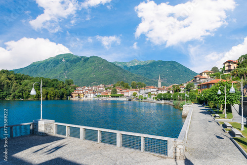 Beautiful Italian lake among the mountains. Lake Mergozzo and Mergozzo town, Italy. Pedestrian promenade along the lake in summer with blue sky. Valle Ossola in Piedmont region