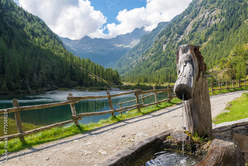 Mountain lake on the alps with a path and a fountain in summer. Macugnaga and lake delle Fate, Italy. The lago delle Fate (fairy lake or lake of the fairies) is an easy excursion suitable for everyone